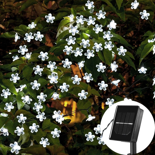 Solar-powered flower-shaped LED Christmas tree lights illuminating a garden at night.