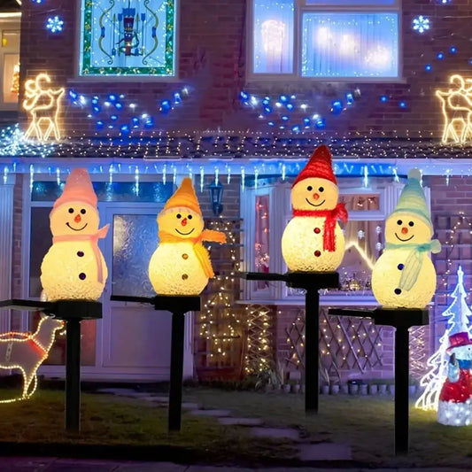 LED snowman solar garden stake lights illuminating a festive outdoor lawn with Christmas decorations.