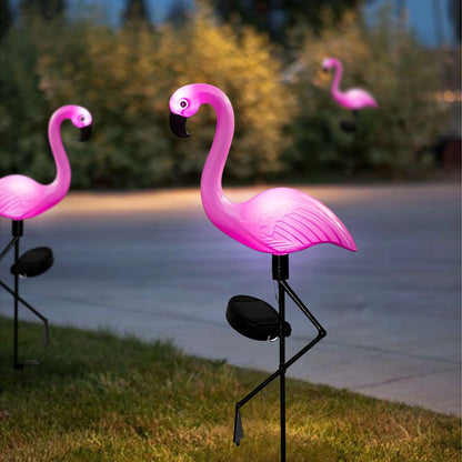 Set of solar flamingo garden lights glowing pink in a grassy outdoor space, perfect for festive or decorative use.