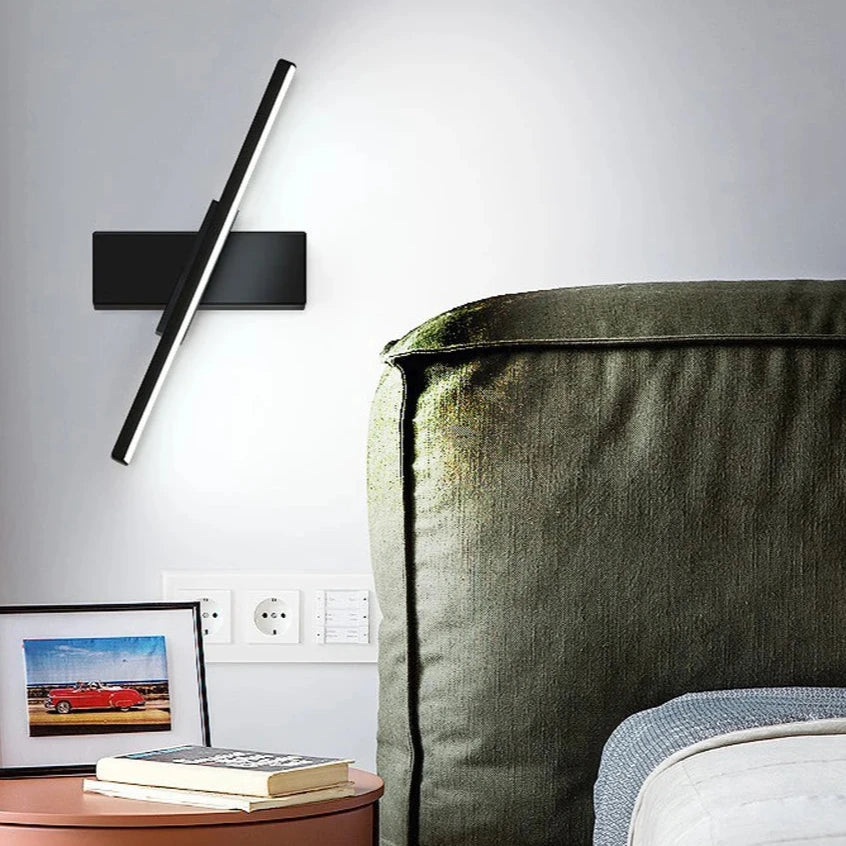 Modern LED wall light with rotatable design installed beside a bed