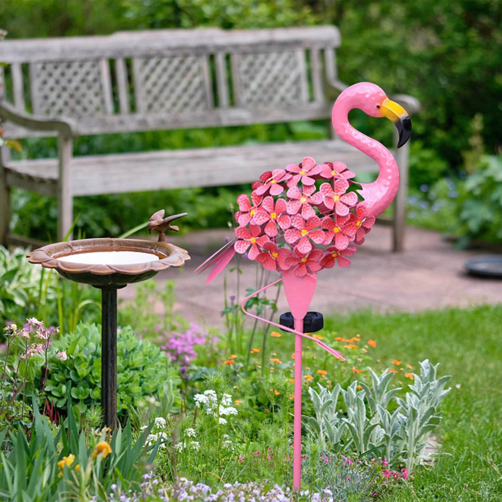 Metal flamingo solar stake light with flower detailing, illuminating a vibrant garden space with eco-friendly LED lighting.