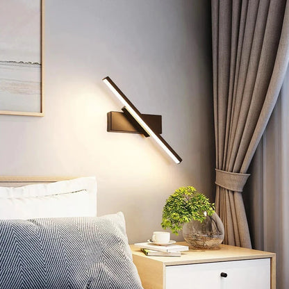 Modern LED wall light with rotatable design installed beside a bed