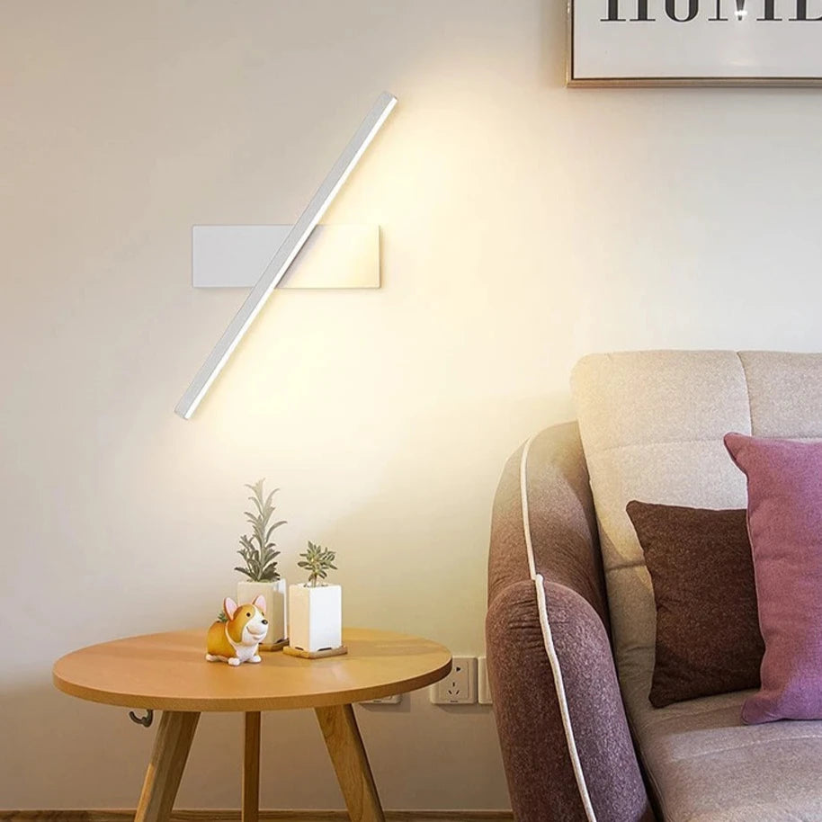 Modern LED wall light with rotatable design installed beside a bed