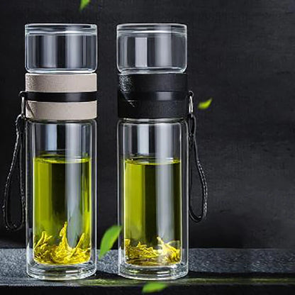 Transparent glass tea tumbler with double-layer design, built-in tea filter, and carrying strap, perfect for loose-leaf tea brewing.