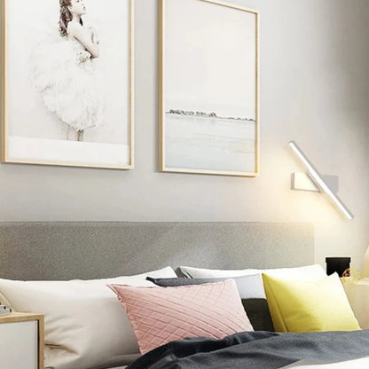 Modern LED wall light with rotatable design installed beside a bed