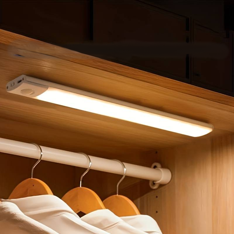 Motion-activated LED bar light installed in a wooden closet, providing warm white lighting with magnetic tape attachment for easy installation.